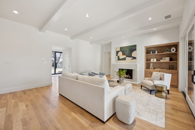 living area featuring baseboards, beamed ceiling, light wood-style floors, a fireplace, and recessed lighting