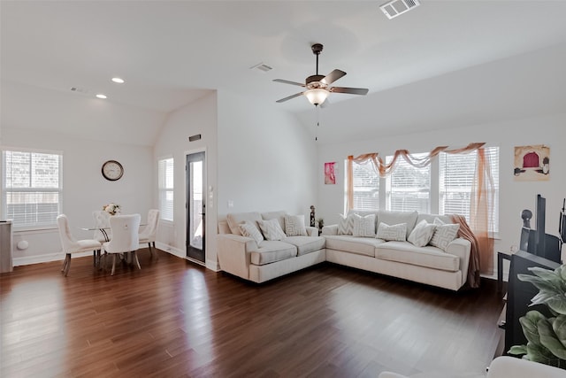 living room featuring dark wood-style flooring, visible vents, and vaulted ceiling