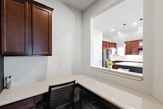 kitchen featuring pendant lighting, light countertops, built in desk, and stainless steel fridge with ice dispenser