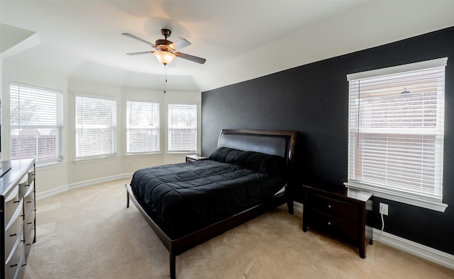 bedroom featuring a ceiling fan, light carpet, vaulted ceiling, and baseboards