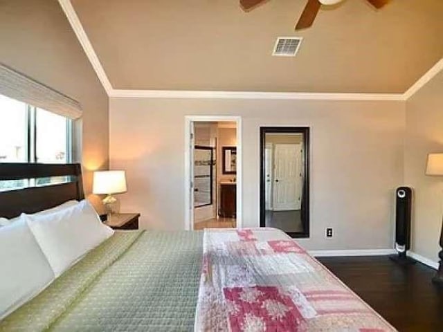 bedroom with dark wood-type flooring, visible vents, baseboards, vaulted ceiling, and crown molding