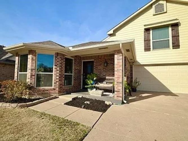 exterior space with brick siding, driveway, an attached garage, and a patio