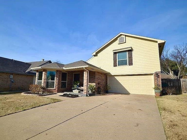 view of front facade with a garage, driveway, brick siding, and fence