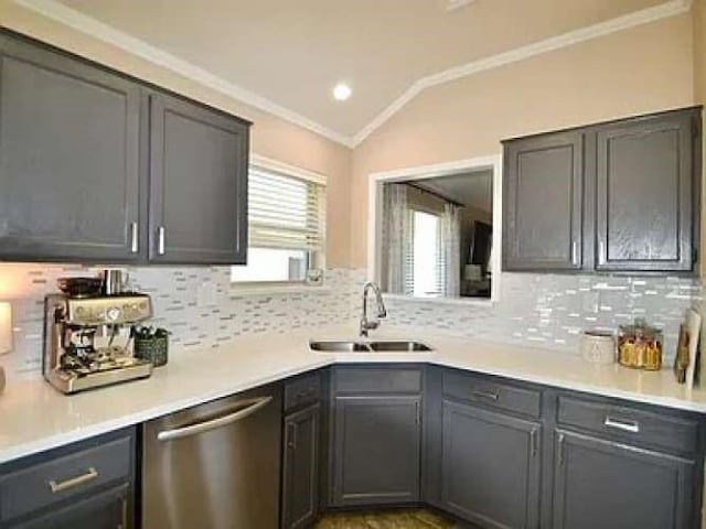 kitchen featuring ornamental molding, backsplash, vaulted ceiling, stainless steel dishwasher, and a sink