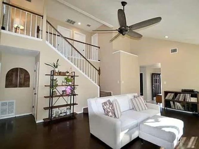 living area featuring a ceiling fan, visible vents, and stairway