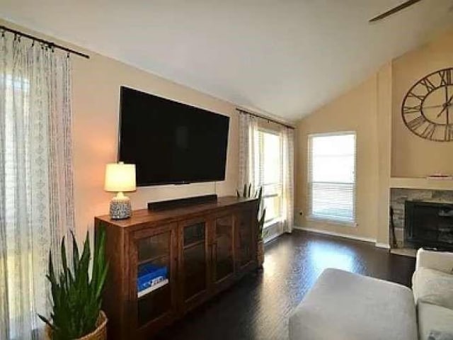 living area featuring lofted ceiling, dark wood finished floors, and a stone fireplace