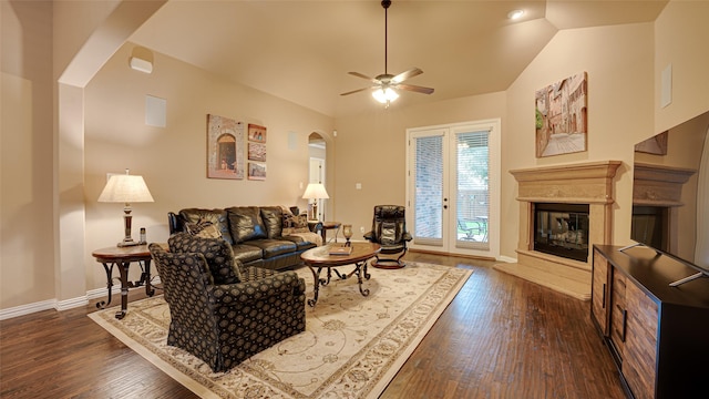 living area with dark wood-style floors, arched walkways, a glass covered fireplace, and vaulted ceiling