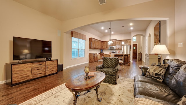 living room featuring dark wood-style floors, visible vents, arched walkways, and baseboards