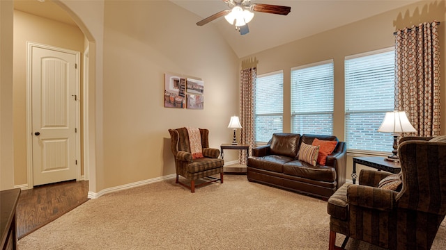 carpeted living area with a ceiling fan, arched walkways, lofted ceiling, and baseboards