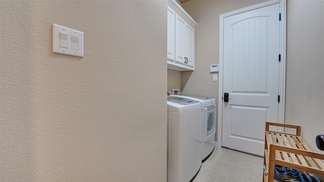 laundry room featuring a textured wall, washing machine and dryer, and cabinet space