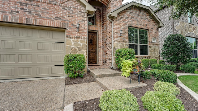 view of exterior entry featuring brick siding and an attached garage