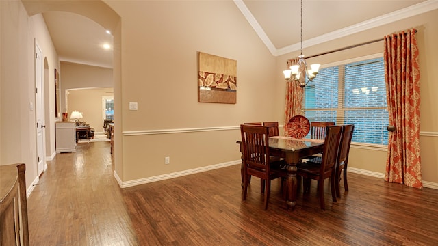 dining room with baseboards, arched walkways, ornamental molding, wood finished floors, and a notable chandelier