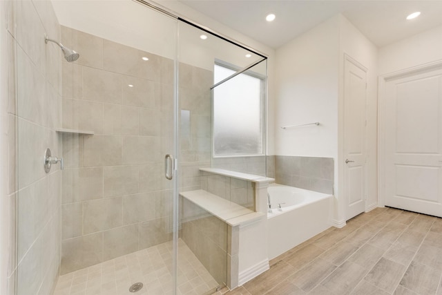 full bathroom with a shower stall, a bath, and recessed lighting