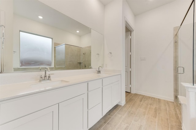 bathroom featuring double vanity, a shower stall, a sink, and recessed lighting