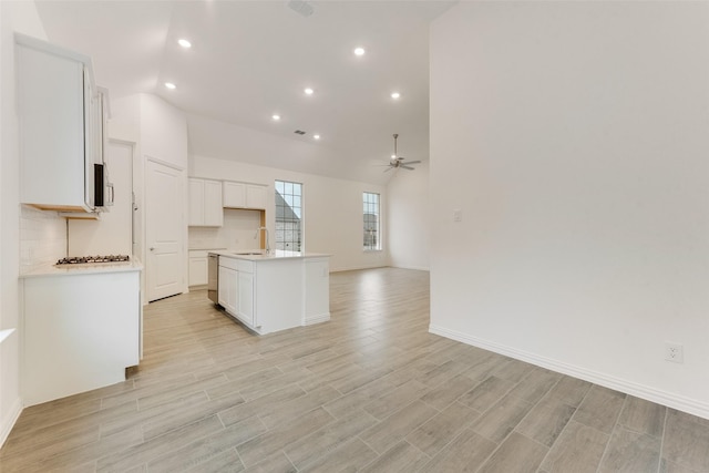 kitchen featuring light wood-style flooring, a ceiling fan, open floor plan, white cabinets, and a sink