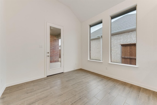 empty room featuring baseboards, vaulted ceiling, and light wood finished floors