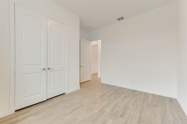 unfurnished bedroom featuring light wood-style floors, baseboards, and visible vents