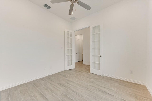 spare room featuring french doors, visible vents, light wood-style floors, a ceiling fan, and baseboards