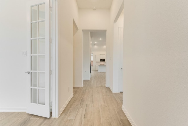 hallway featuring light wood-style flooring and baseboards