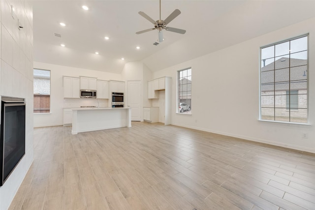 unfurnished living room featuring a ceiling fan, baseboards, light wood-style flooring, and a tiled fireplace