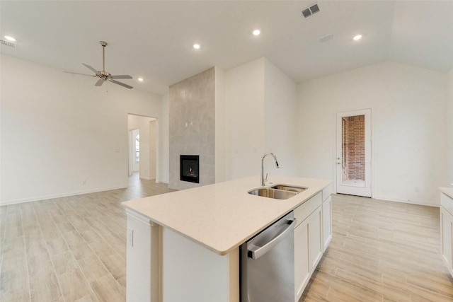 kitchen with a fireplace, a sink, visible vents, white cabinets, and stainless steel dishwasher