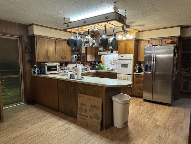 188 Walker Rd, Olney, TX 76374 - kitchen with stainless steel fridge, a peninsula, light wood finished floors, a textured ceiling, and light countertops