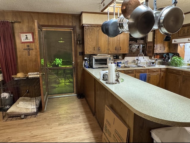 188 Walker Rd, Olney, TX 76374 - kitchen with a textured ceiling, light countertops, wooden walls, a sink, and light wood-style floors
