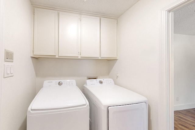 laundry room featuring washer and dryer, a textured ceiling, wood finished floors, and cabinet space