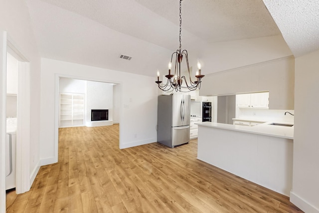 unfurnished dining area with light wood-type flooring, a fireplace, vaulted ceiling, and a sink