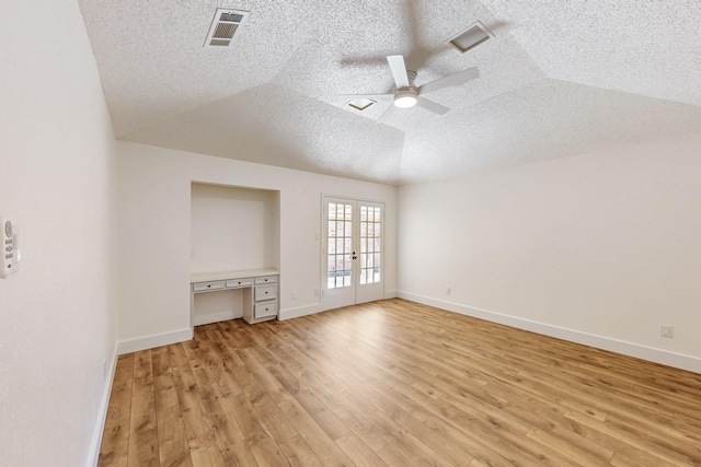 interior space featuring a ceiling fan, light wood finished floors, a textured ceiling, and visible vents