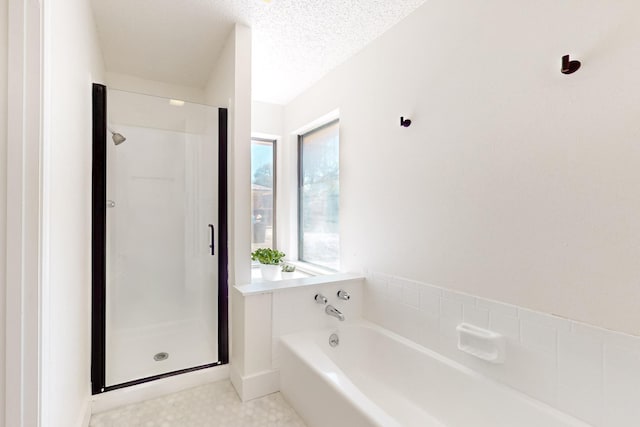 bathroom with a stall shower, a textured ceiling, and a bath