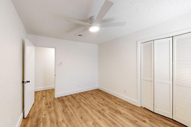 unfurnished bedroom with a textured ceiling, a ceiling fan, baseboards, light wood-type flooring, and a closet