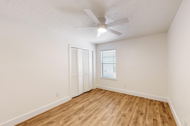 unfurnished bedroom featuring light wood finished floors, a textured ceiling, baseboards, and a closet