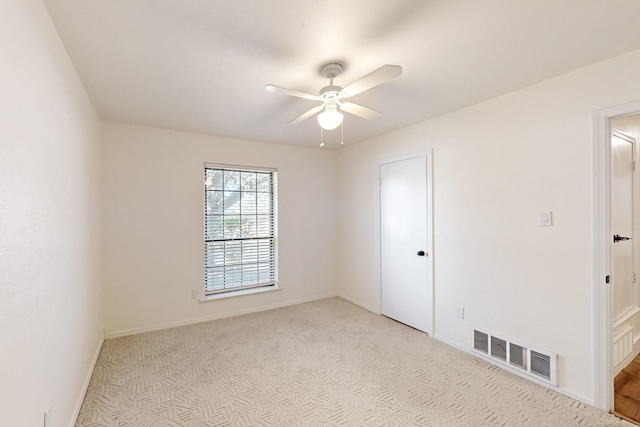 spare room featuring baseboards, ceiling fan, light colored carpet, and visible vents