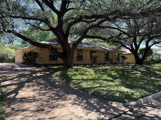 ranch-style house featuring brick siding, driveway, and a front yard