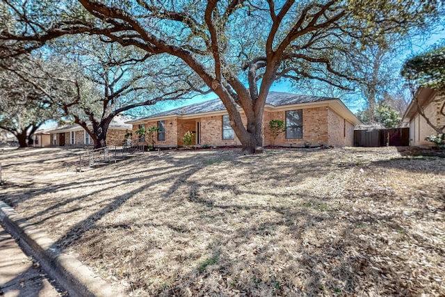 ranch-style home featuring brick siding and fence