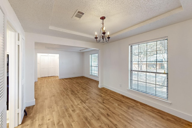 spare room with visible vents, a textured ceiling, baseboards, and a chandelier