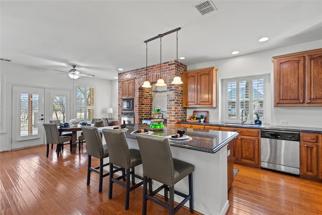 kitchen with stainless steel appliances, dark countertops, visible vents, and a sink