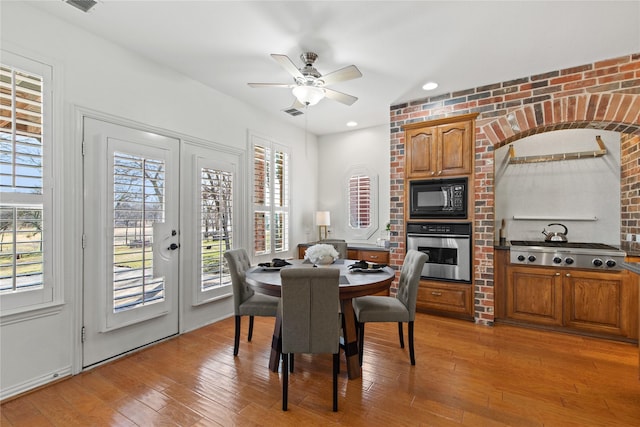 dining area with light wood-type flooring, a healthy amount of sunlight, ceiling fan, and visible vents