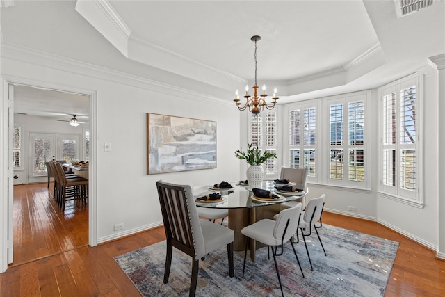 dining room featuring a raised ceiling, visible vents, crown molding, and wood-type flooring