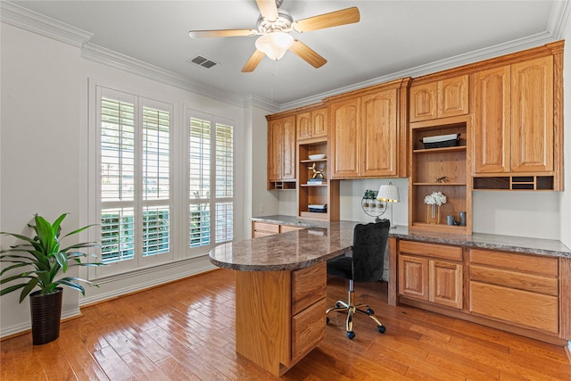 kitchen with visible vents, ornamental molding, light wood-style floors, open shelves, and built in desk