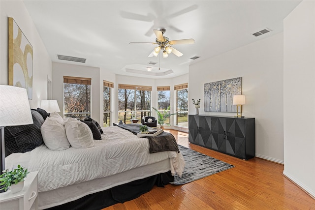 bedroom with wood finished floors, visible vents, and access to exterior