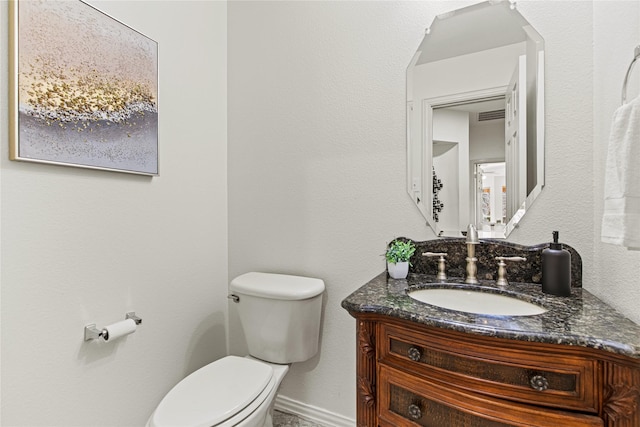 half bathroom featuring vanity, toilet, and baseboards