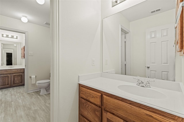 bathroom with visible vents, vanity, toilet, and wood finished floors