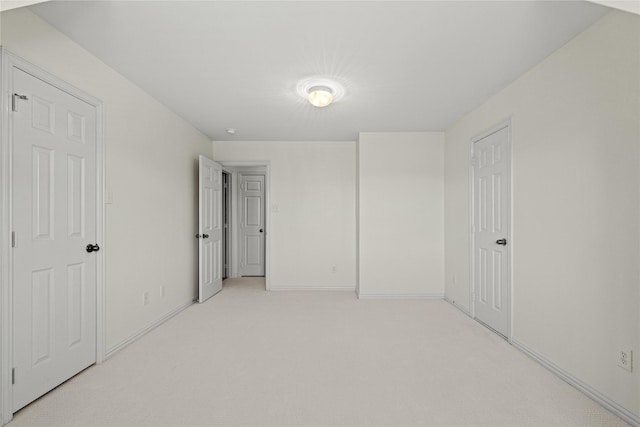 unfurnished bedroom with light colored carpet and baseboards