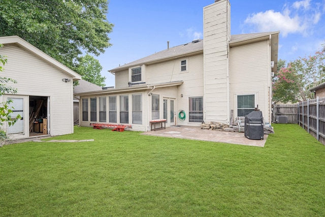 back of property featuring a lawn, a chimney, a fenced backyard, and a sunroom