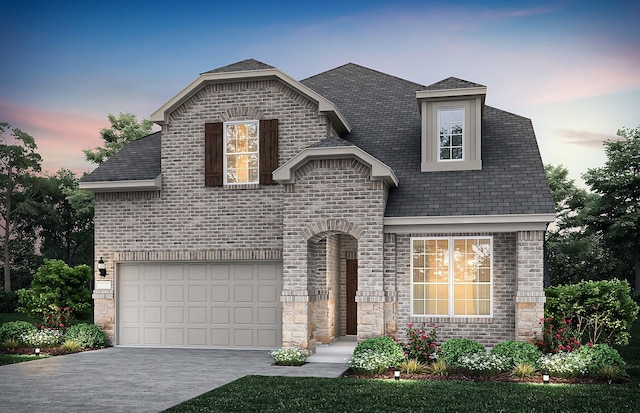 french provincial home featuring stone siding, concrete driveway, brick siding, and an attached garage