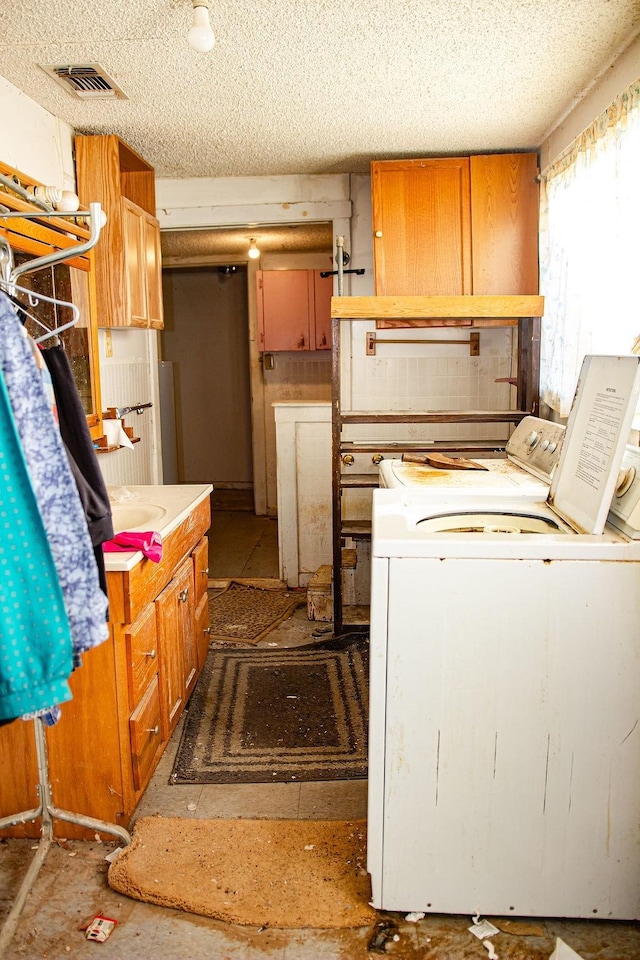 laundry area with visible vents, a textured ceiling, cabinet space, and washer and dryer