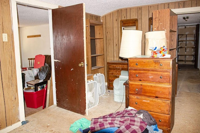 bedroom featuring wooden walls and a textured ceiling