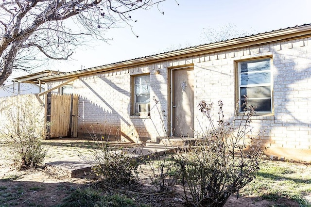 view of side of home featuring metal roof, brick siding, and fence